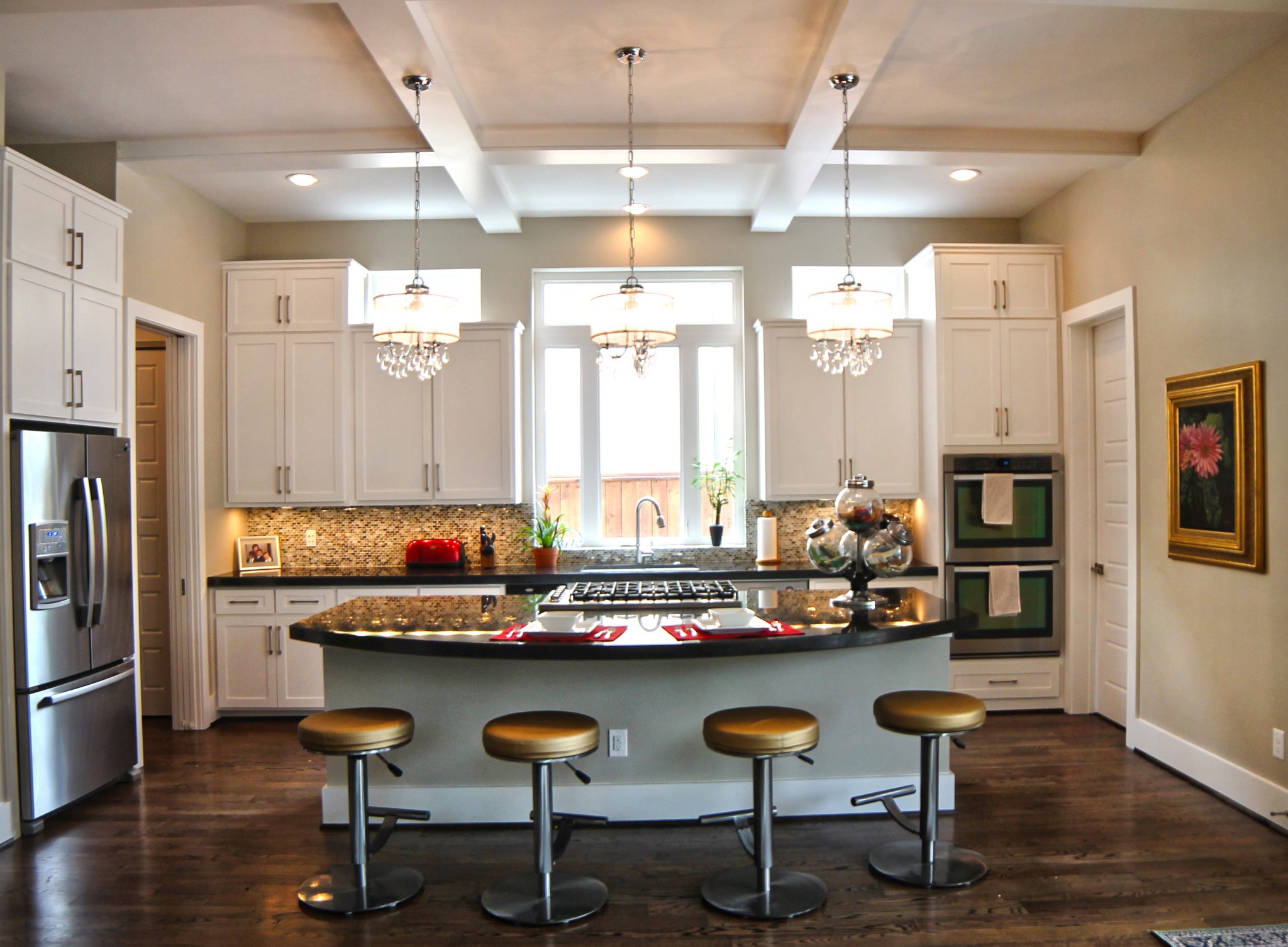 Kitchen with white cabinetry, a central island, pendant lights, and wood flooring